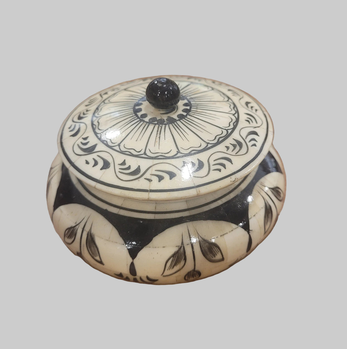 Round cream bone trinket box with black hand painted lotus design and black knob lid