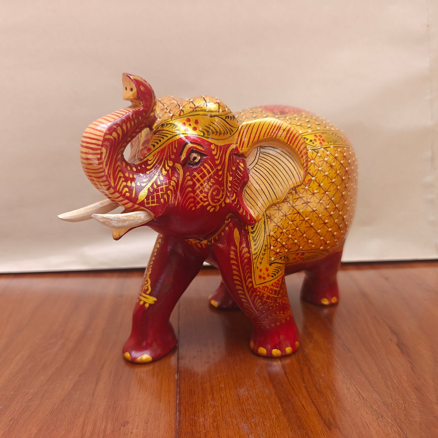 Red and yellow handpainted elephant decor displayed on wooden table