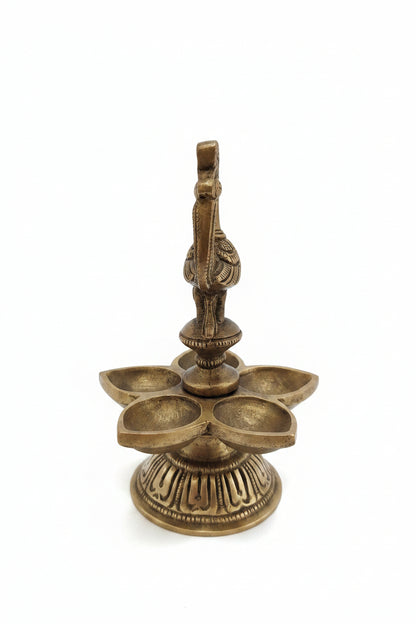 Handcrafted brass peacock diya with 5 petal-shaped oil wicks and intricate engraved base, traditional South Indian temple lamp