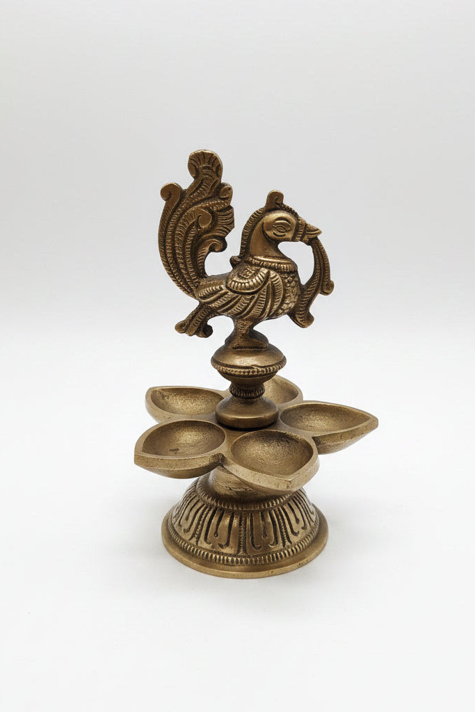 Handcrafted brass peacock diya with 5 petal-shaped oil wicks and intricate engraved base, traditional South Indian temple lamp