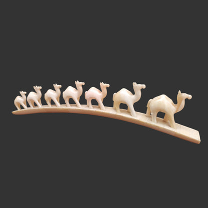 Carved bone camel parade on arched base displayed