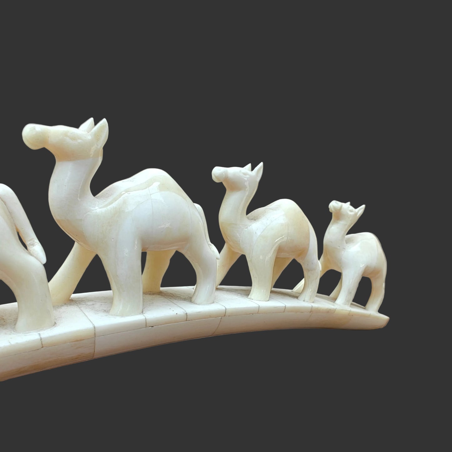 Close-up of carved bone camels at the front of the parade on arched base
