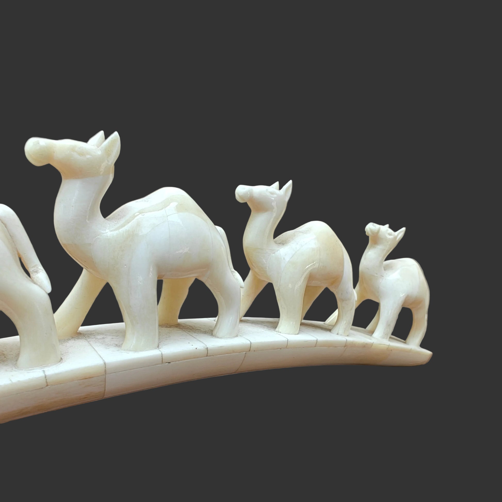 Close-up of carved bone camels at the front of the parade on arched base