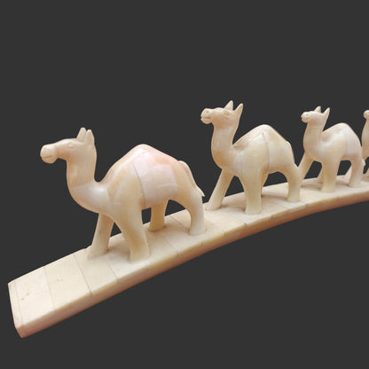 Close-up of carved bone camels standing in a row on arched base