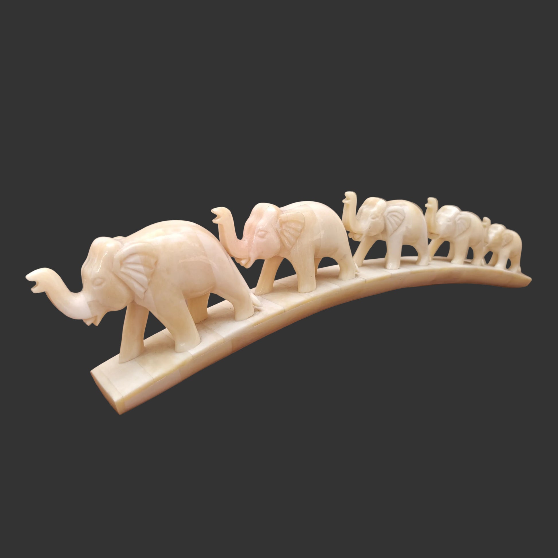 Side view of carved bone elephant parade showing elephants walking across arched base

