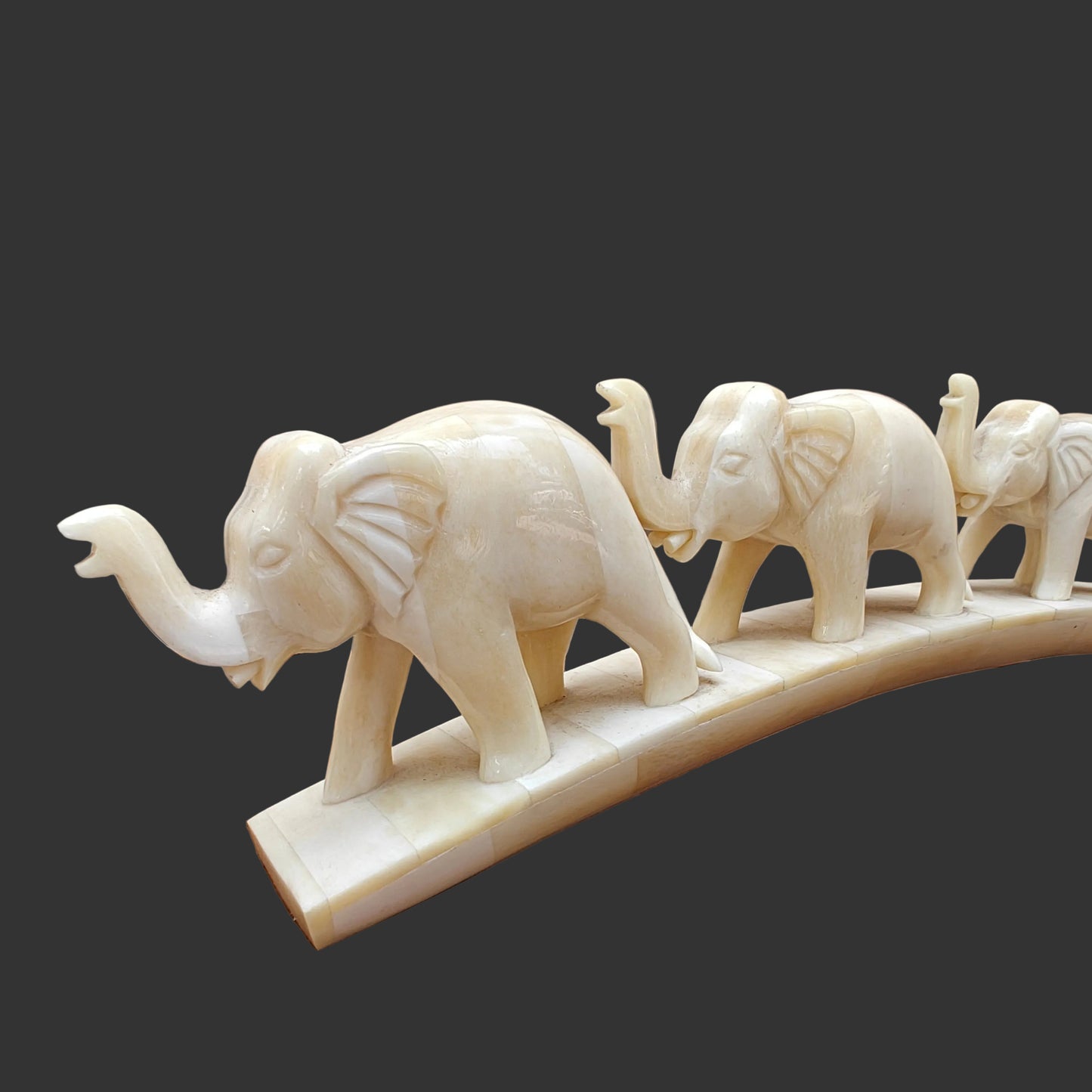 Close-up of carved bone elephants at the front of the parade on arched base