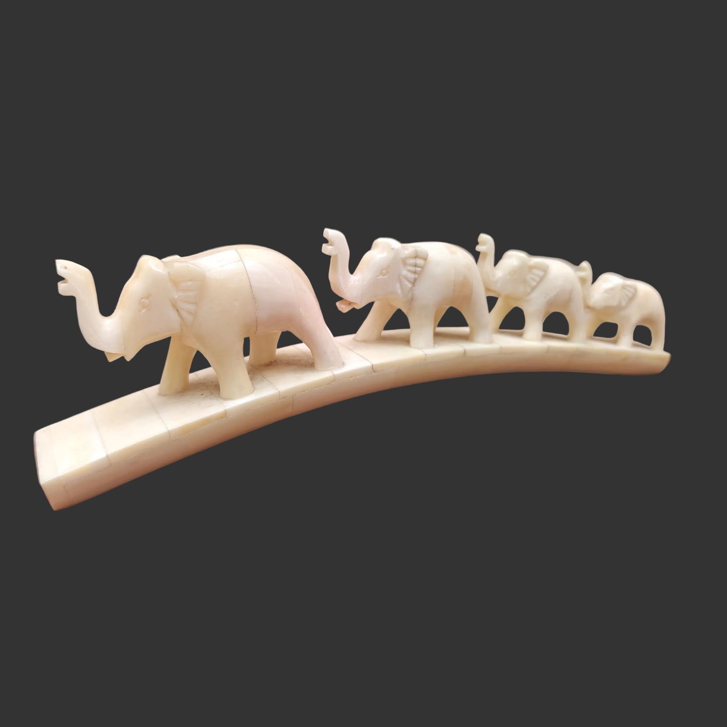 Side view of carved bone four-camel parade showing animals walking across arched base