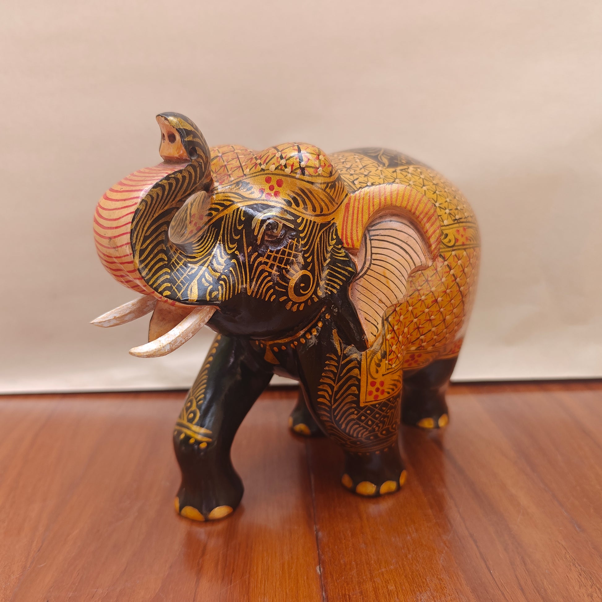 Handpainted black and ochre elephant figurine with intricate golden detailing – front view