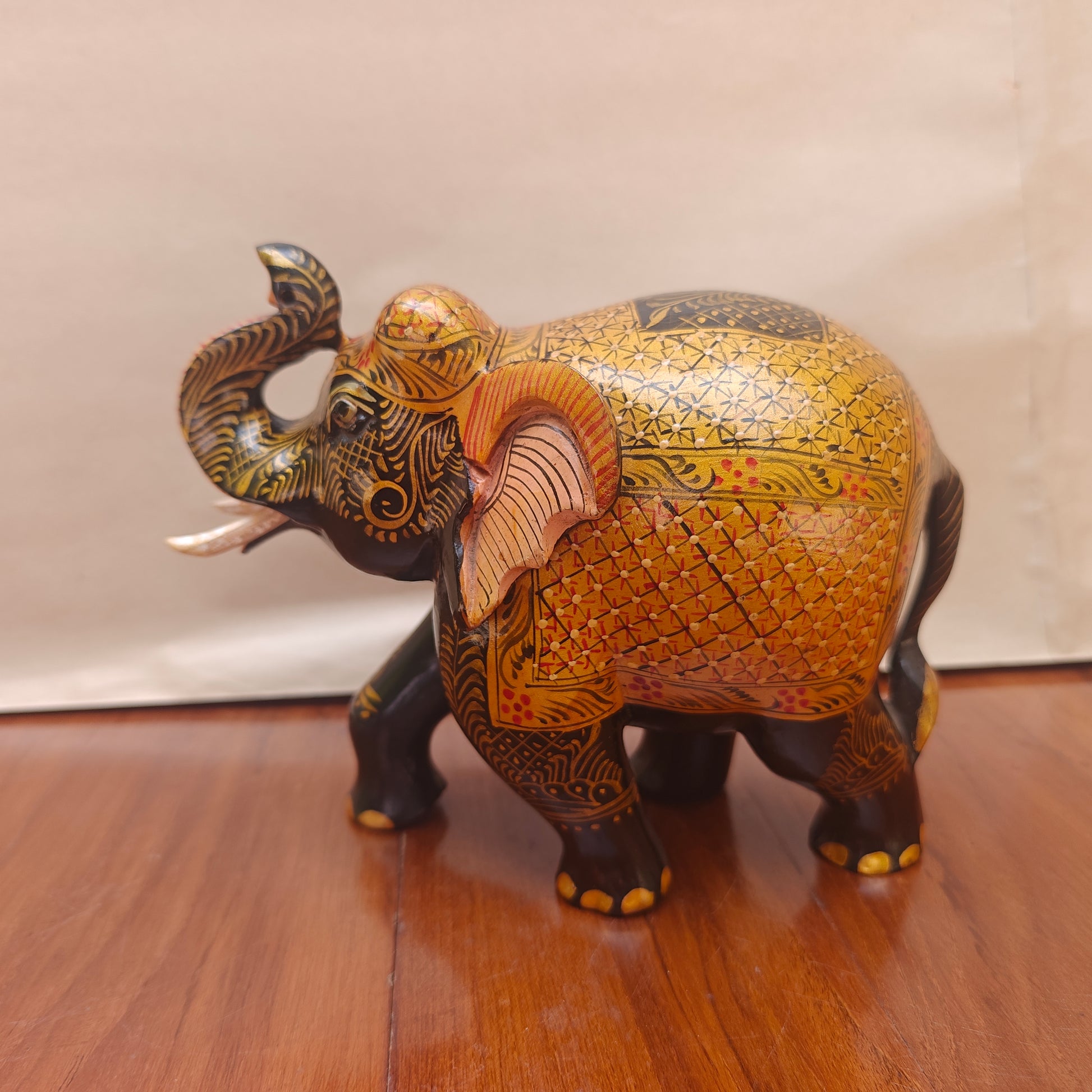 Close-up of patterned head and tusks on black and ochre handpainted elephant figurine