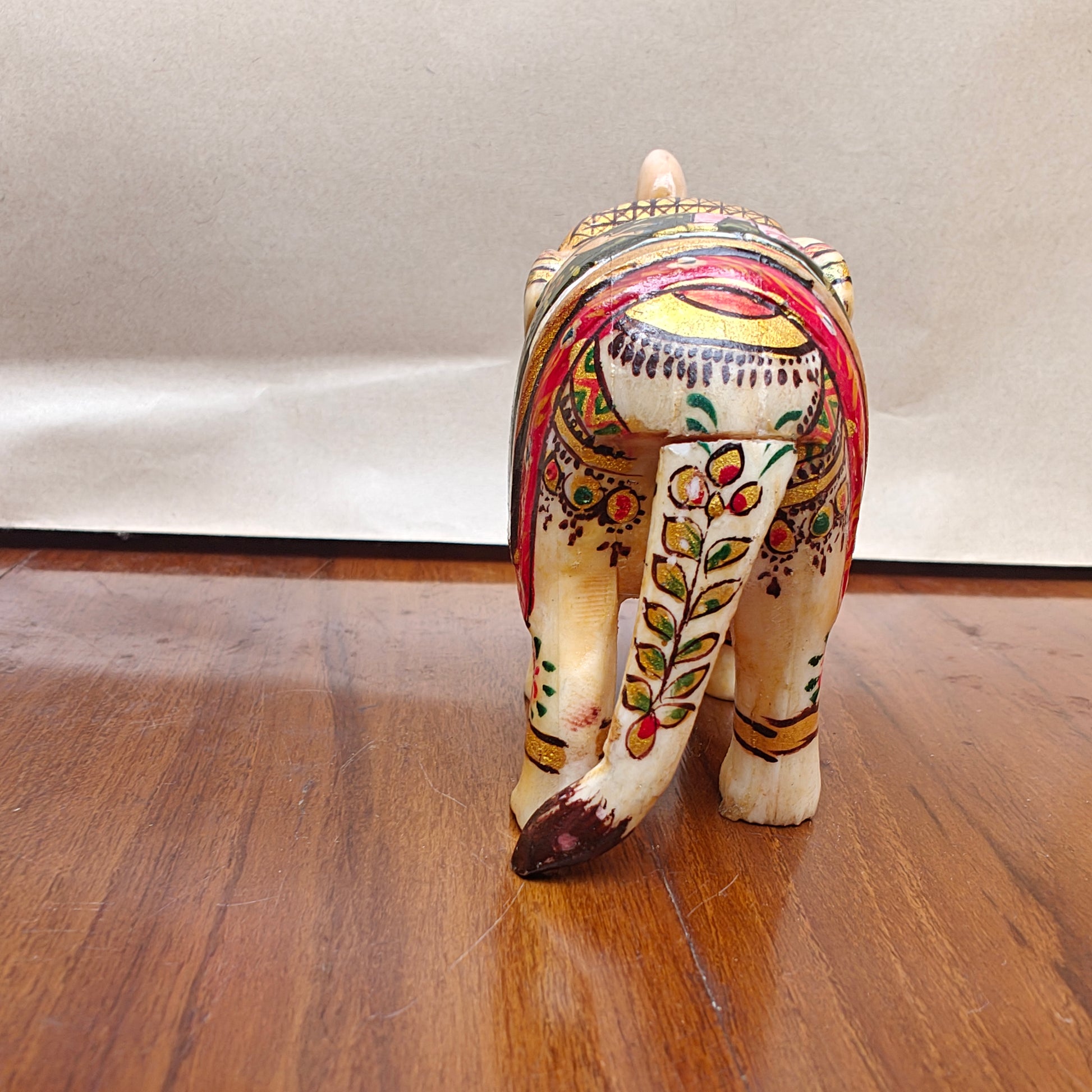 Detail of colourful floral and animal artwork on saddle of handpainted mini bone elephant decor piece