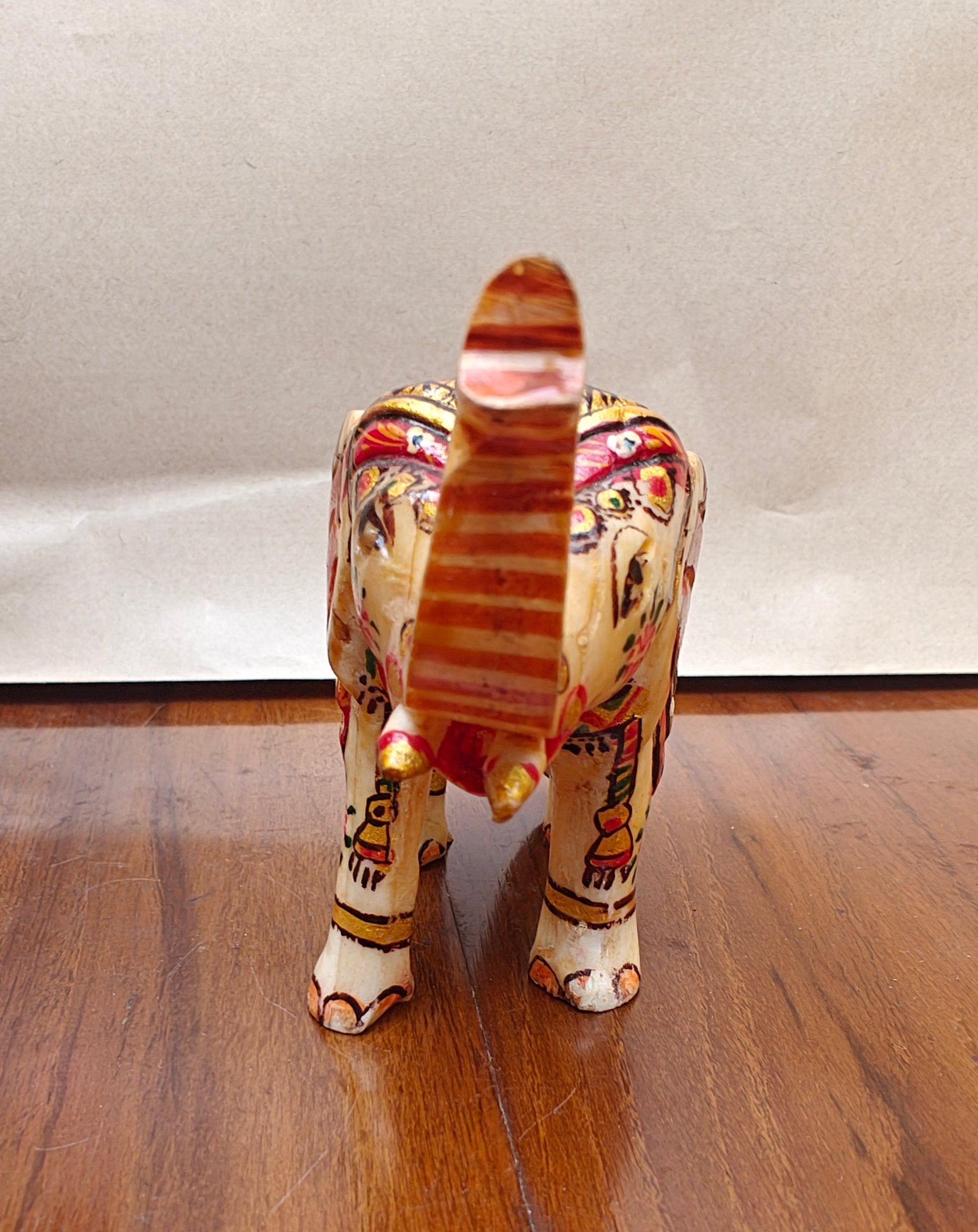 Close-up of painted head, ears and raised trunk on mini bone elephant figurine