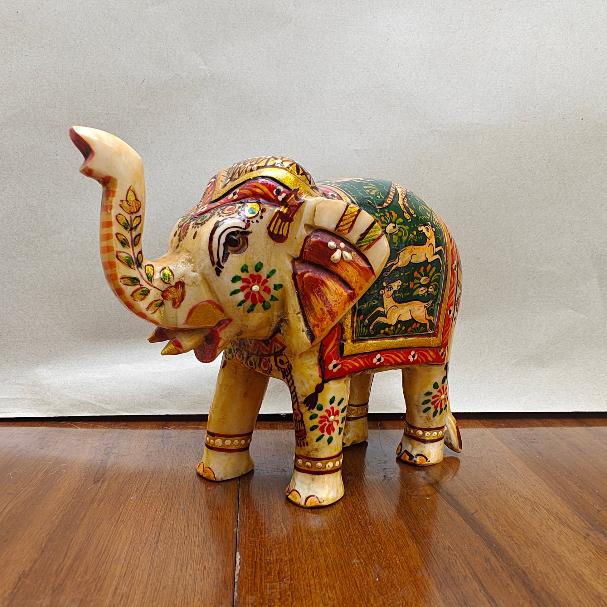 Side profile of handpainted bone elephant decor showing detailed painted scene