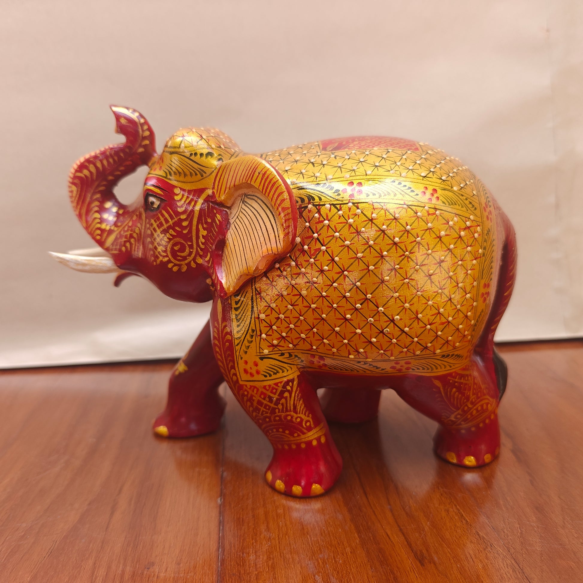 Close-up of golden handpainted floral and geometric detailing on red and yellow elephant figurine