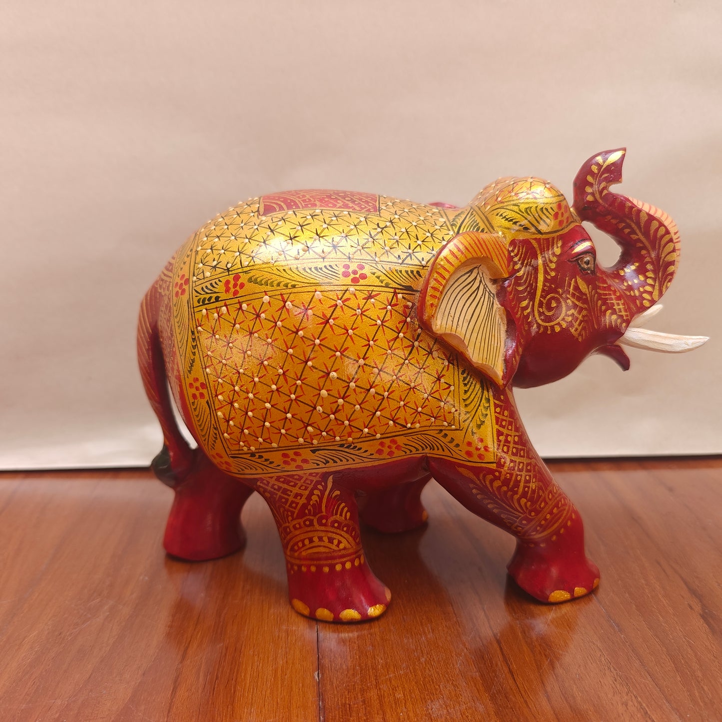 Side view of handpainted red and yellow decorative elephant with intricate patterns