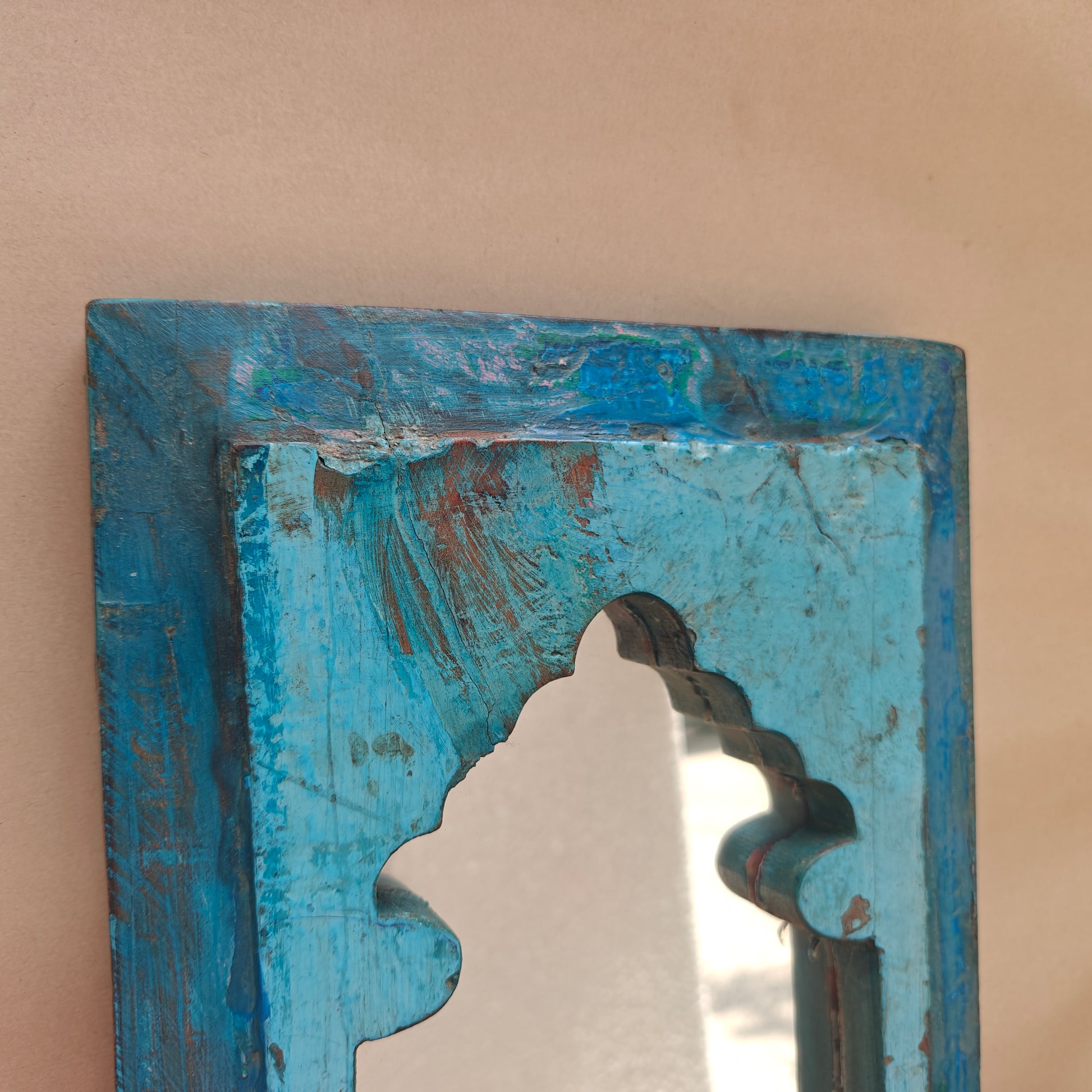 Close up of distressed turquoise paint and wood texture on Jharokha mirror frame corner