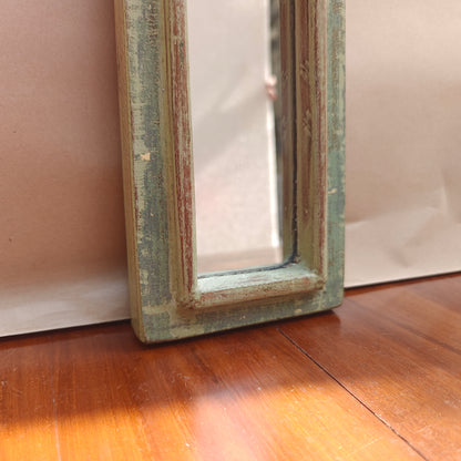 Narrow vintage sage green mirror styled on a console table